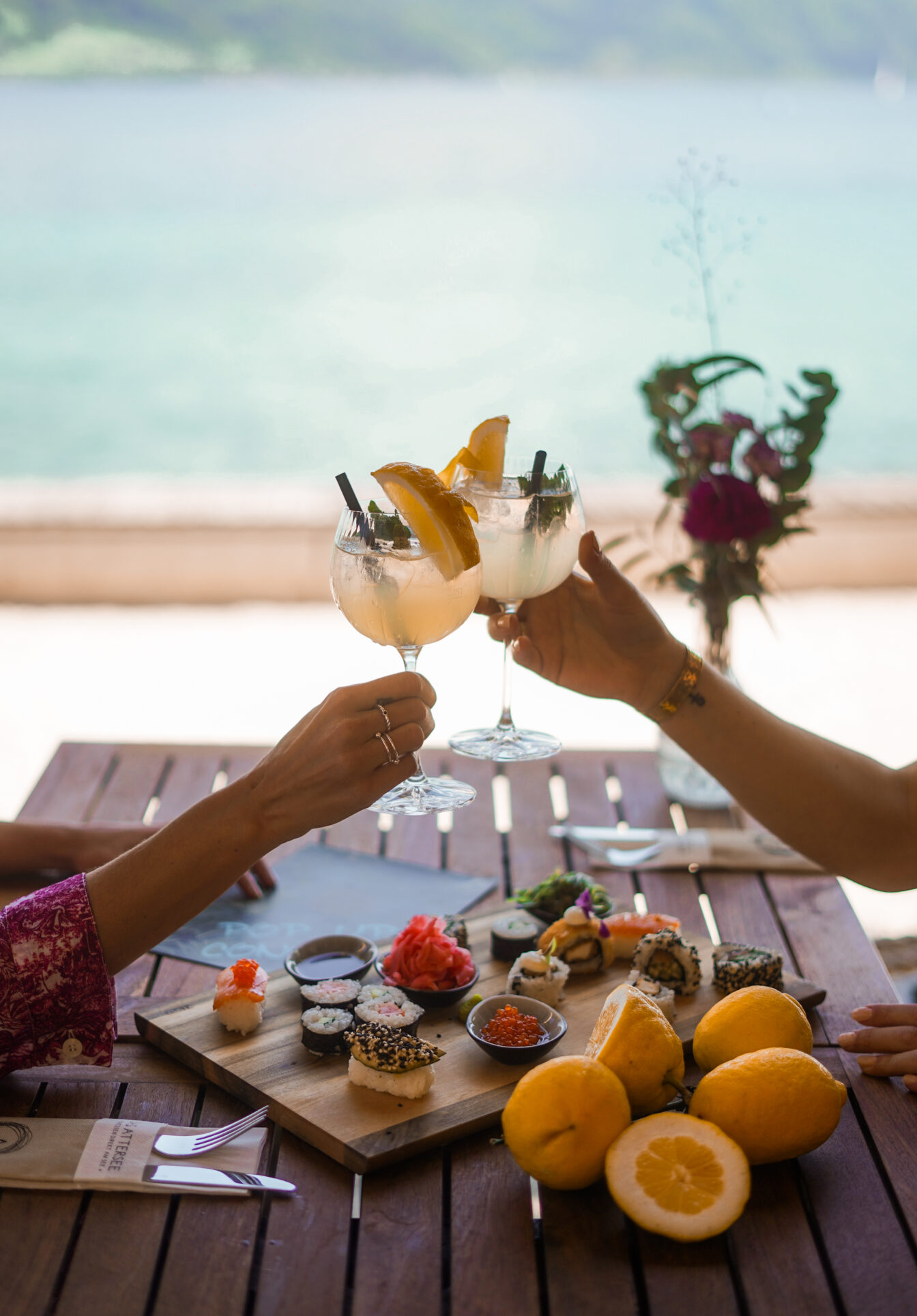 Sushi und Drinks im Restaurant Das Attersee mit dem See im Hintergrund.