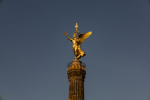 Goldene Statue der Viktoria auf der Berliner Siegessäule vor klarem, blauem Himmel im Abendlicht