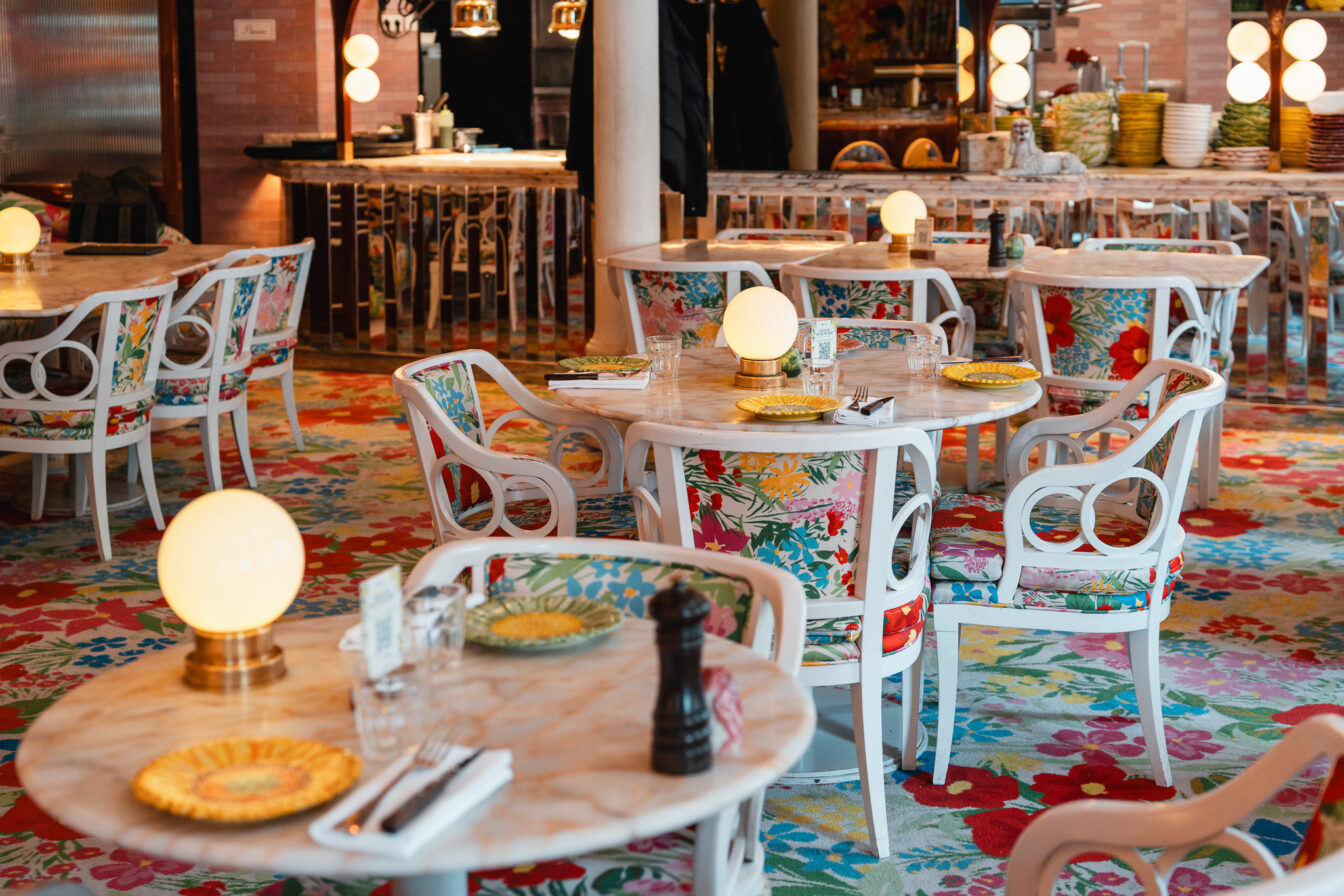 Bunte Blumenmuster auf Tischen und Stühlen in einem Restaurant in München.