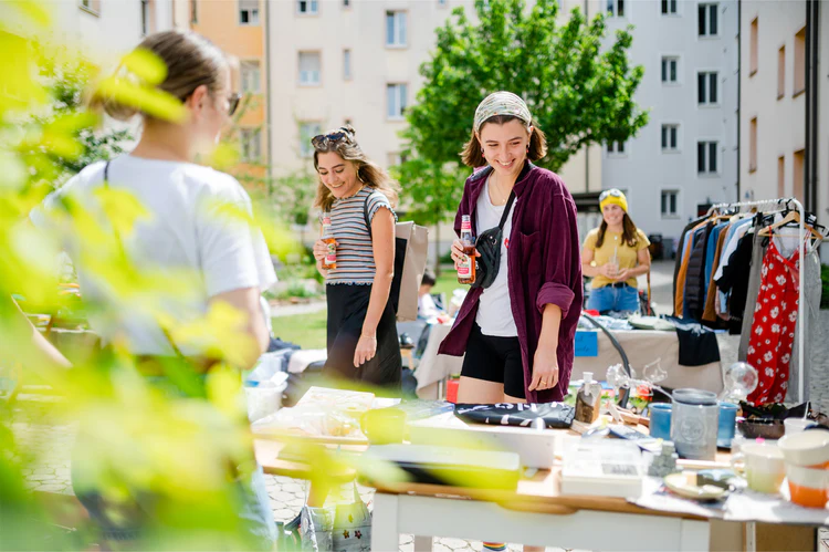 Eine junge Person an einem Flohmarktstand im Hinterhof.