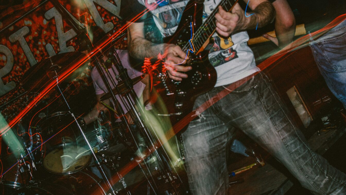 Verschwommene Aufnahme eines Konzerts mit bunten Lichtern und Close-up des Bass-Spielers.