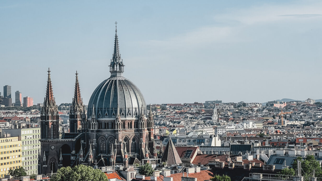 Blick über Wien an einem Sommerabend, der die Skyline freigibt und die Kirche Maria vom Siege zeigt.