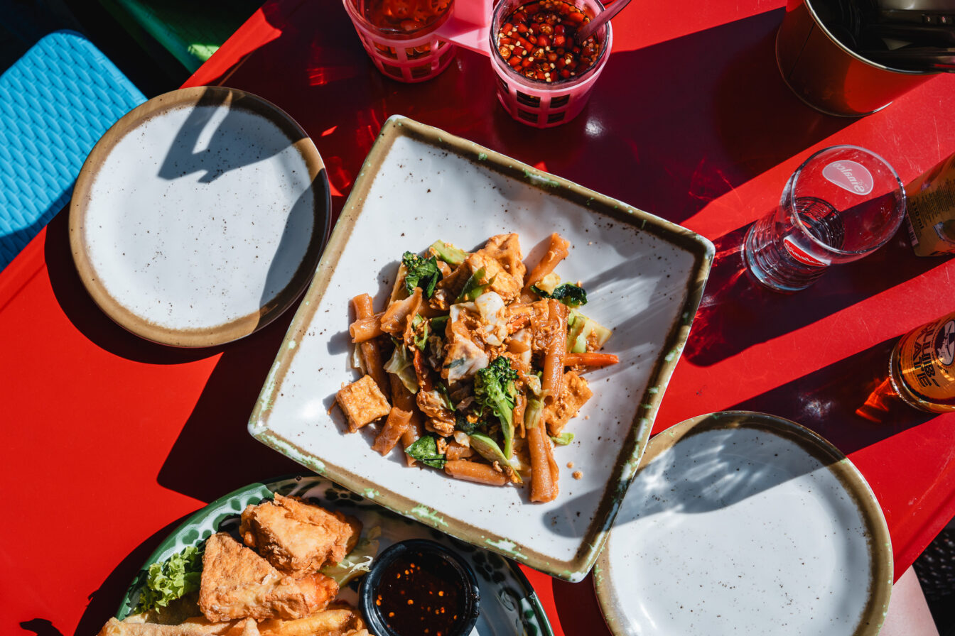 Restaurant in München mit thailändischer Küche und Nightmarket-Flair. Pad Thai auf einem roten Tisch.