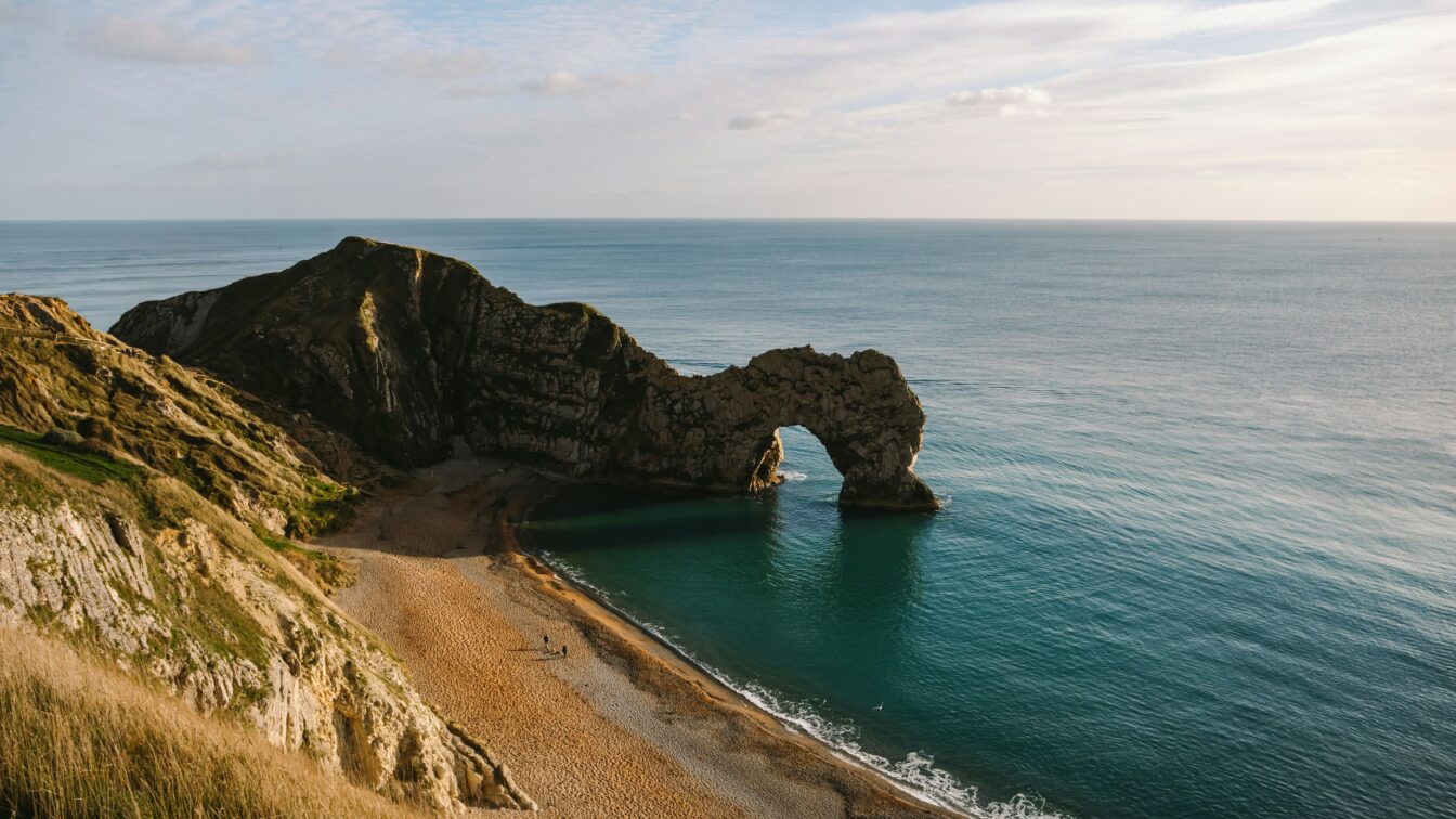 Blick von einer Klippe aus auf eine Felsenformatione, die ins Wasser ragt.