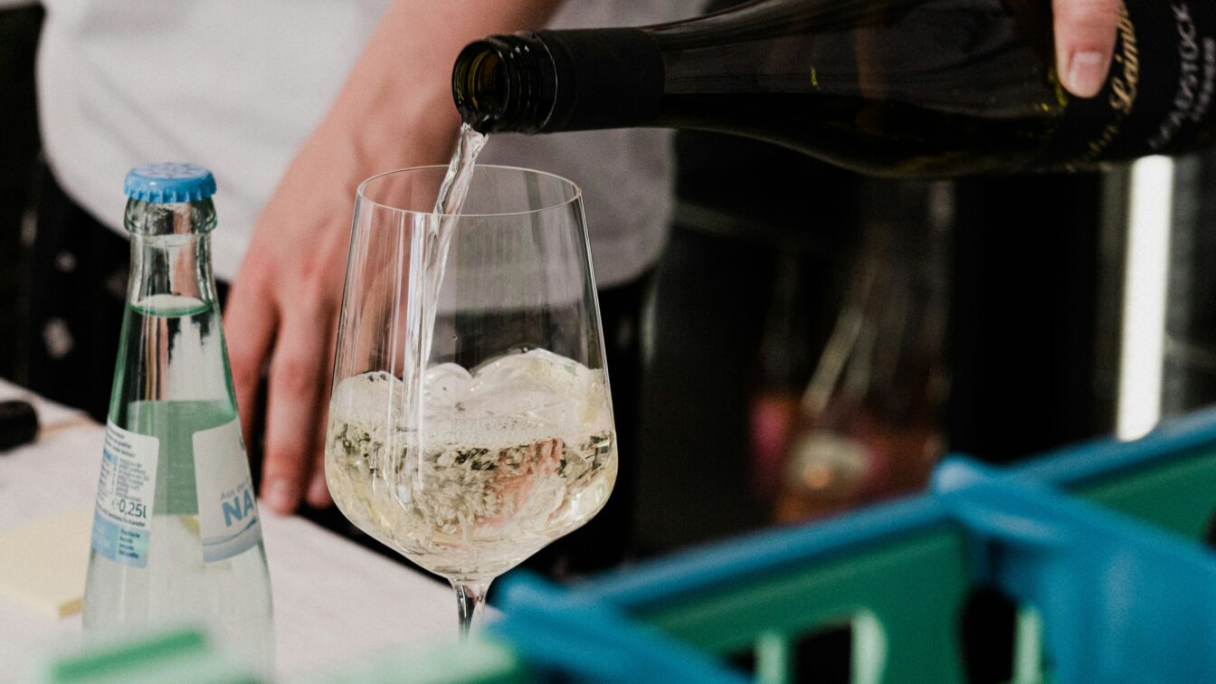 eine Person gießt Wein in ein Weinglas