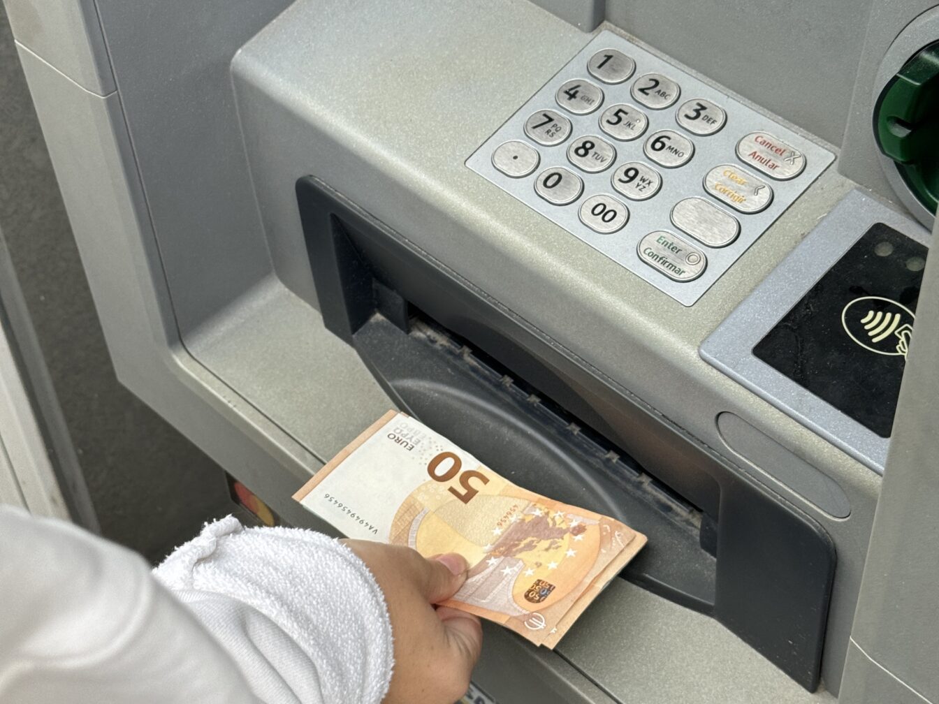Person hebt am Bankomaten Geld in Euro ab