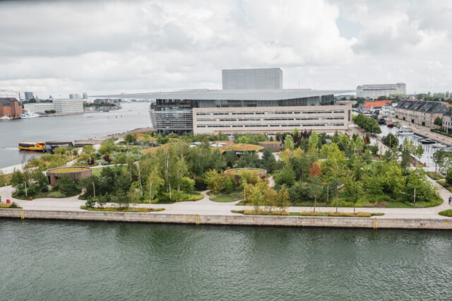 Blick auf ein modernes Gebäude mit umgebendem Park am Wasser