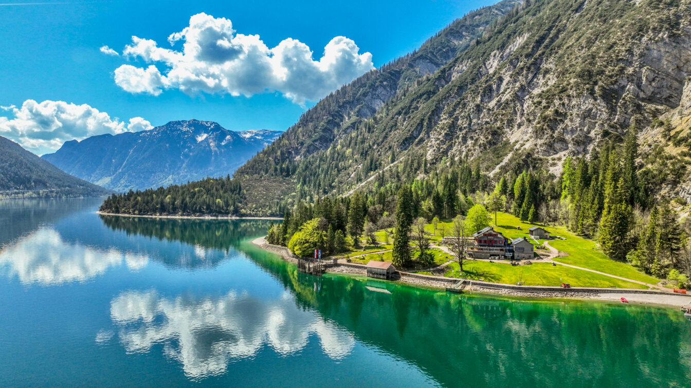 Die Gaisalm ist von saftigen Wiesen und dichten Wäldern umgeben. Bei schönem Wetter spiegeln sich die Wolken verträumt im klaren Wasser des Achensees. /// The Gaisalm mountain hut is surrounded by lush meadows and dense forests. On clear days, clouds reflect dreamily in the clear waters of Lake Achensee.