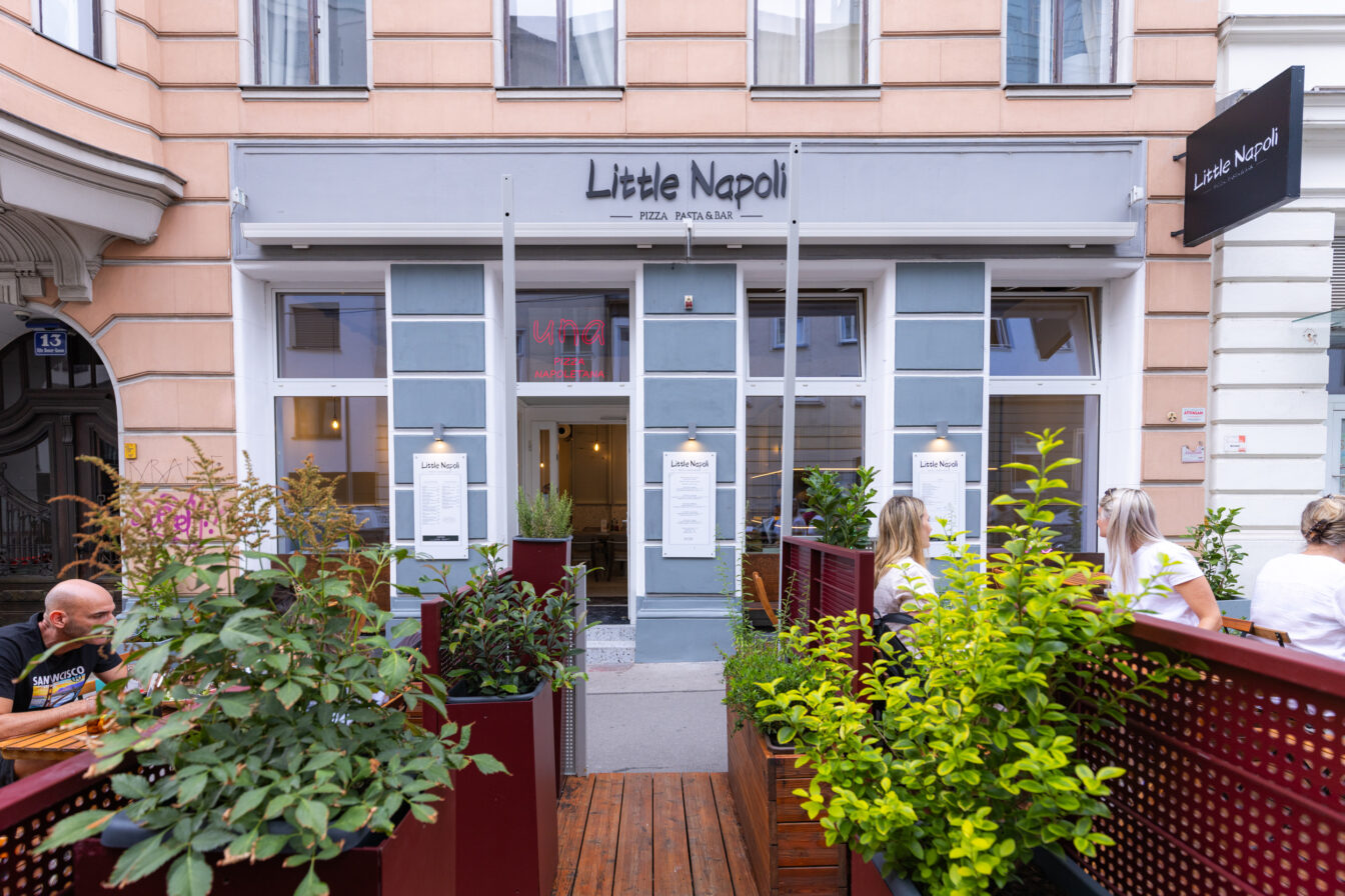 Eingangsbereich des italienischen Restaurants „Little Napoli“ im 6. Bezirk in Wien mit Außenbereich, Sitzgelegenheiten, Pflanzen und sichtbarer Speisekarte an der Fassade.