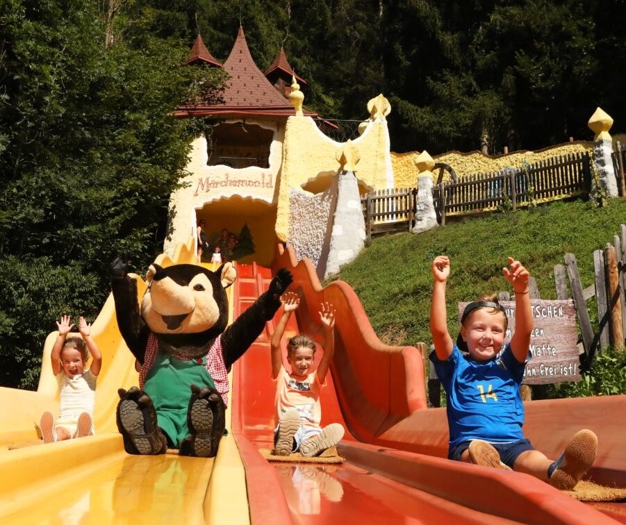 Kinder und ein Maskottchen auf einer bunten Rutsche