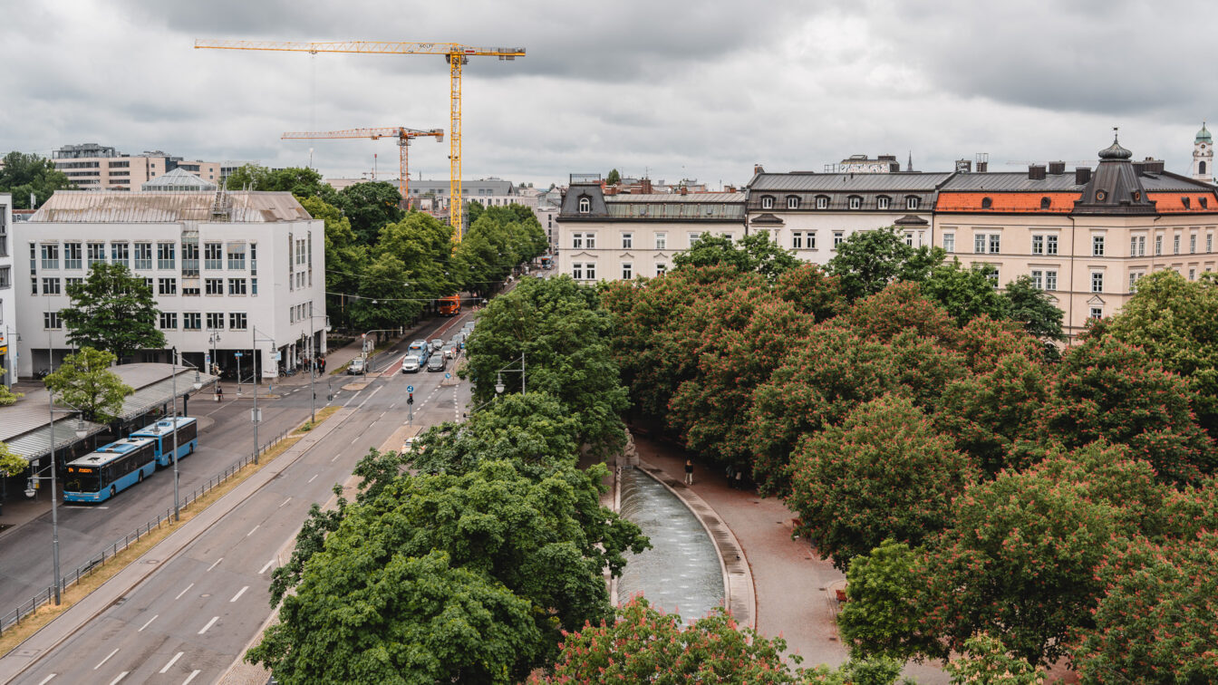 Blick von oben auf einen begrünten Platz am Münchner Ostbahnhof bei Regen.