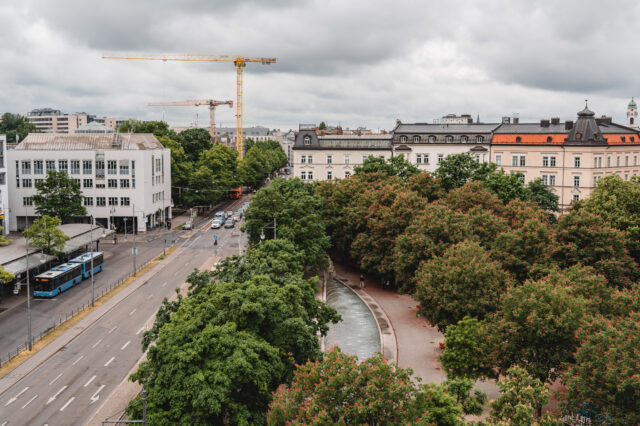 Blick von oben auf einen begrünten Platz am Münchner Ostbahnhof bei Regen.