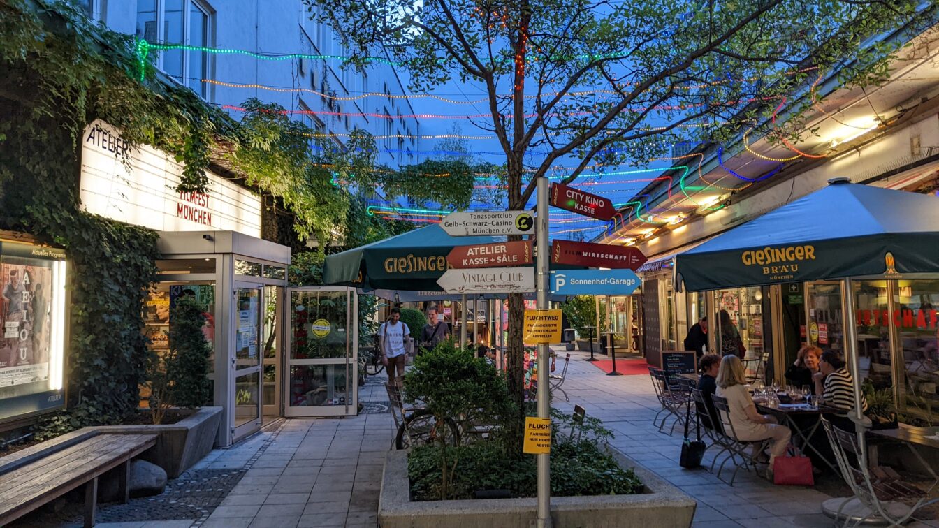 ein beleuchteter Innenhof mit vielen Schildern und Filmplakaten