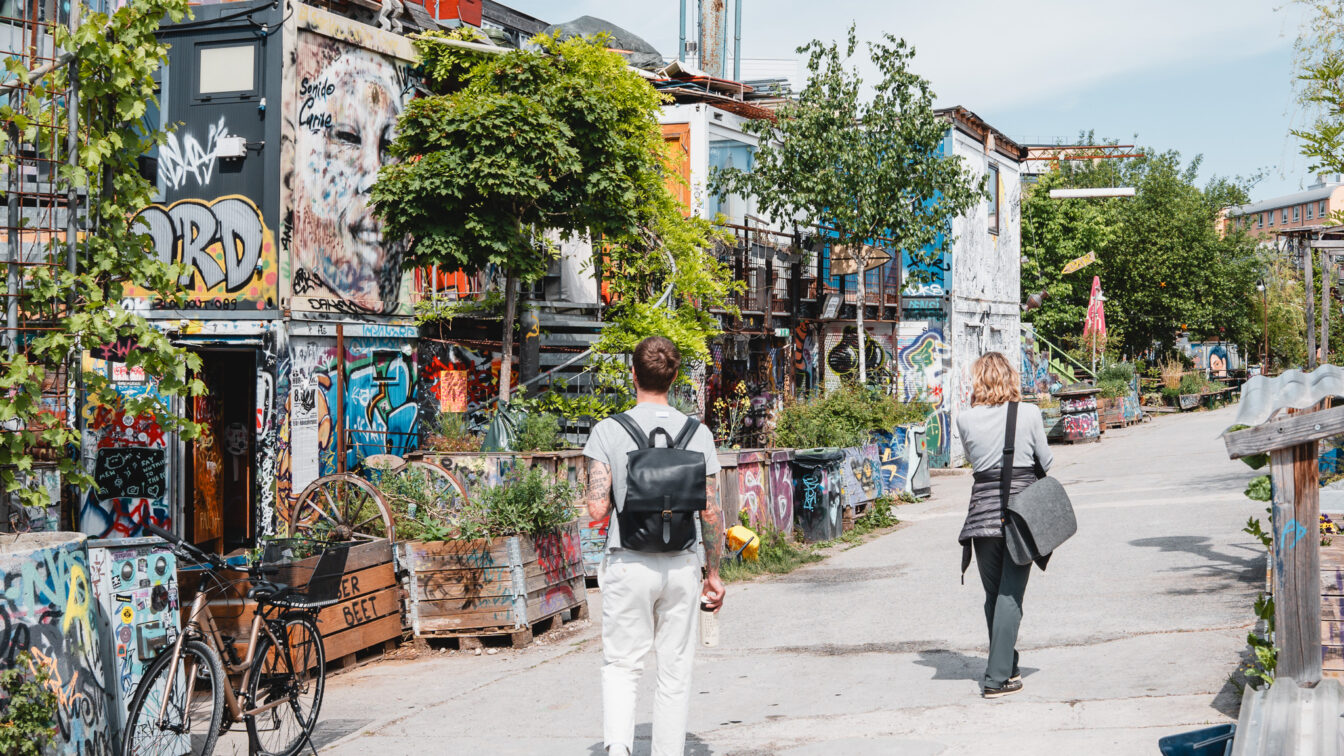 Zwei Personen, die über ein begrüntes Areal aus alten Containern spazieren.