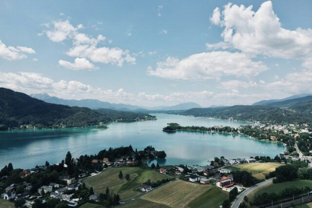 Blick auf einen kleinen Ort am See mit hügeliger Landschaft im Hintergrund