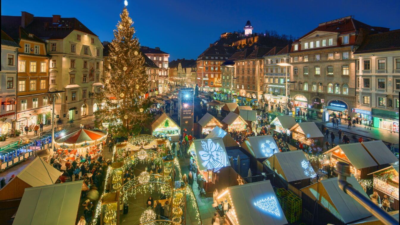 Der Adventmarkt am Grazer Hauptplatz aus der Vogelperspektive. Es ist dunkel und man sieht viele glitzernde Beleuchtungen.