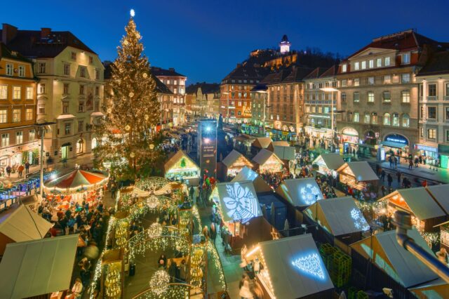 Der Adventmarkt am Grazer Hauptplatz aus der Vogelperspektive. Es ist dunkel und man sieht viele glitzernde Beleuchtungen.