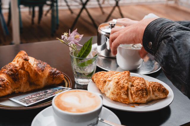 Ein gedeckter Cafétisch mit Kaffee und Croissants in München.