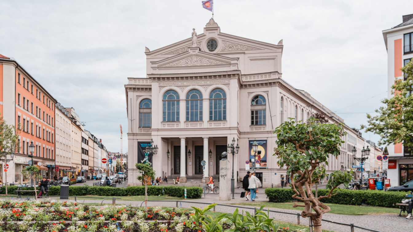 Blumenbeete auf einem runden Platz vor einem imposanten Theater im Glockenbachviertel München.