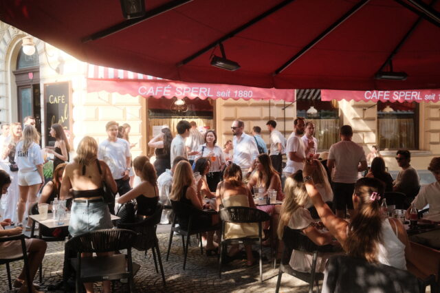 Eine Menge junger Menschen vor einem Wiener Kaffeehaus im Gastgarten.