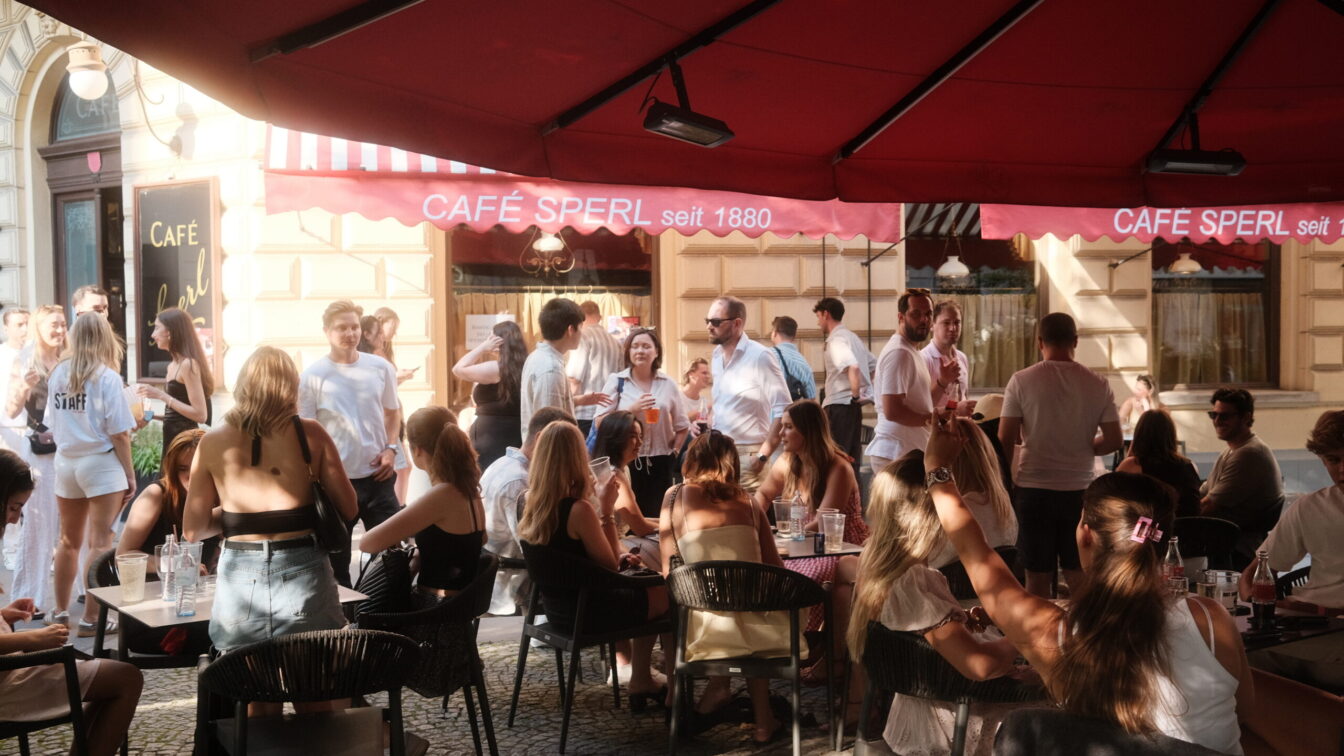 Eine Menge junger Menschen vor einem Wiener Kaffeehaus im Gastgarten.