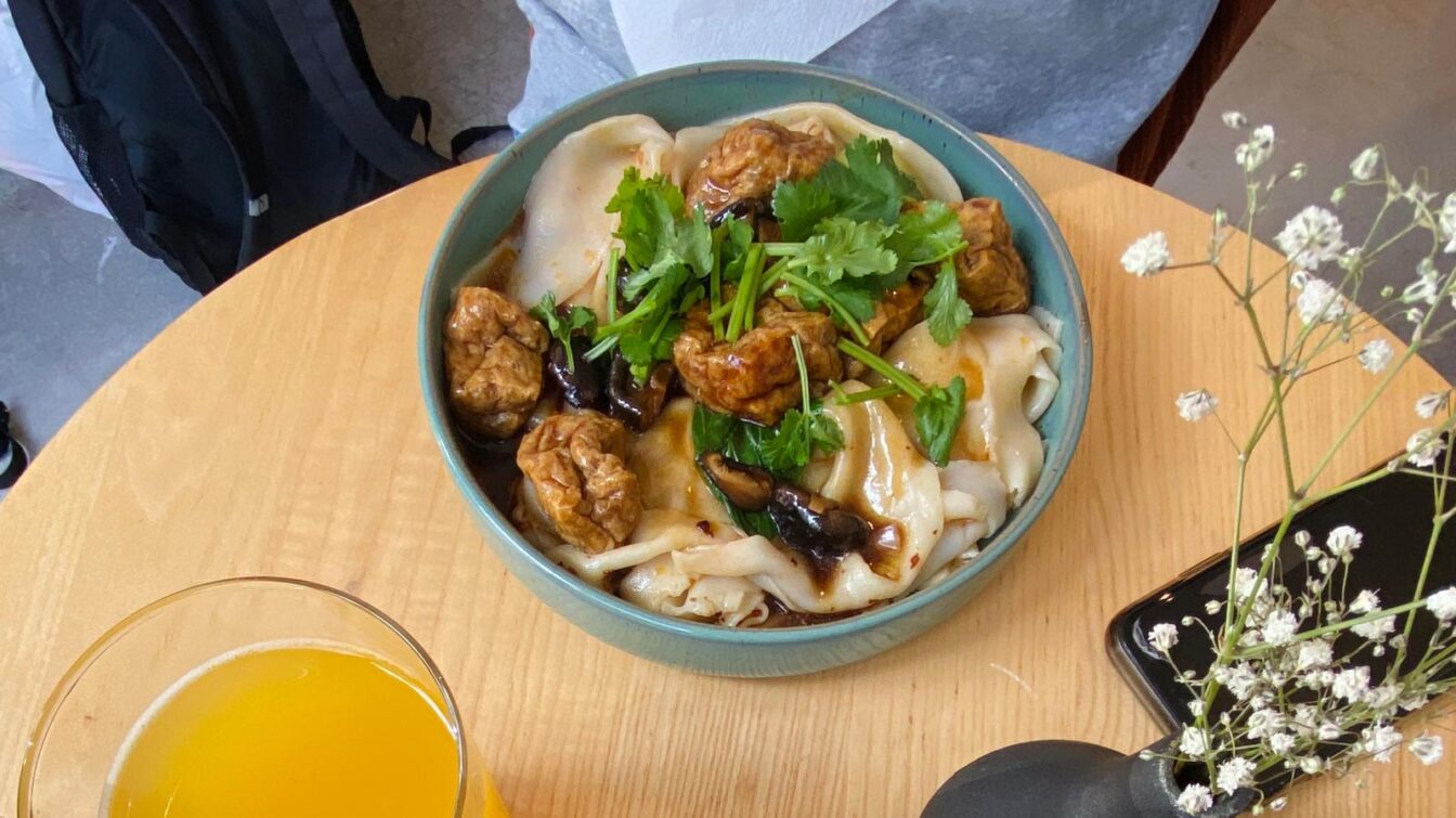 Eine Schale mit einem asiatischen Nudelgericht auf einem kleinen Tisch im einem Restaurant