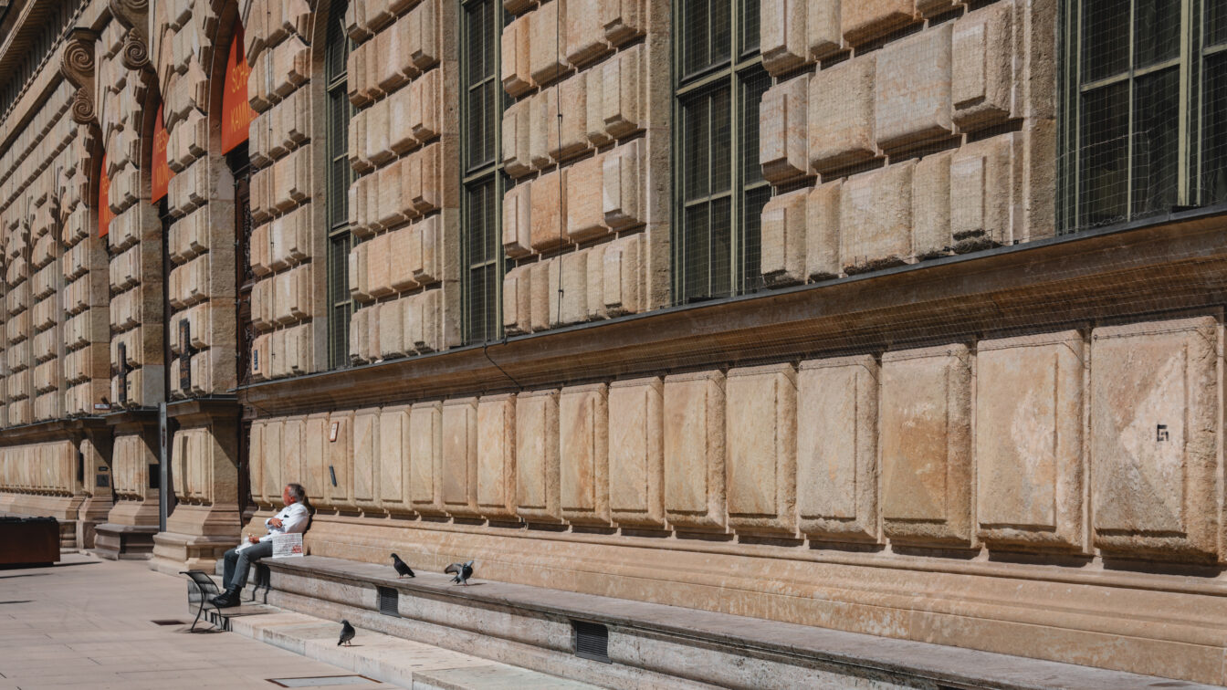 Eine lange Mauer im italienischen Stil mit einer Person, die die Sonne genießt.