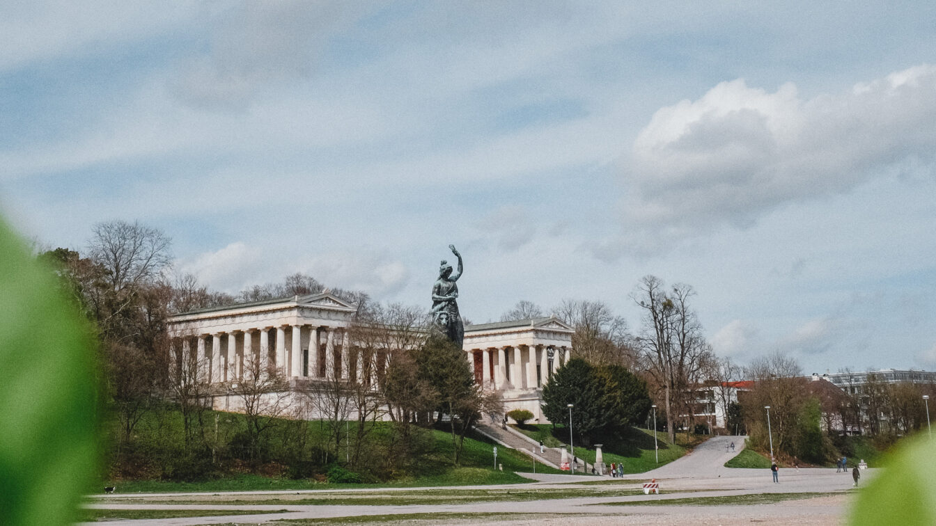 Ein großer Platz mit einer Statue einer Frau am Ende und Säulenhalle