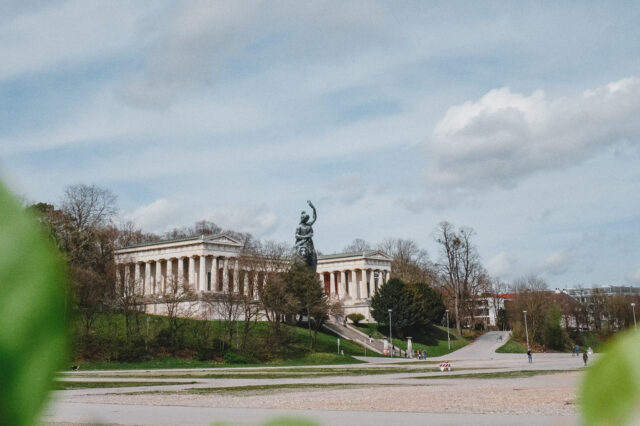 Ein großer Platz mit einer Statue einer Frau am Ende und Säulenhalle