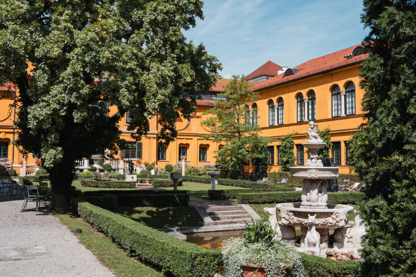 orangenes Renaissancehaus mit grünem Garten und Brunnen