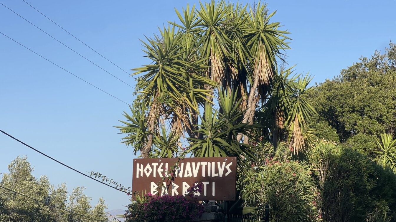 Ein Hotelschild mit Palmen und Bäumen im Hintergrund