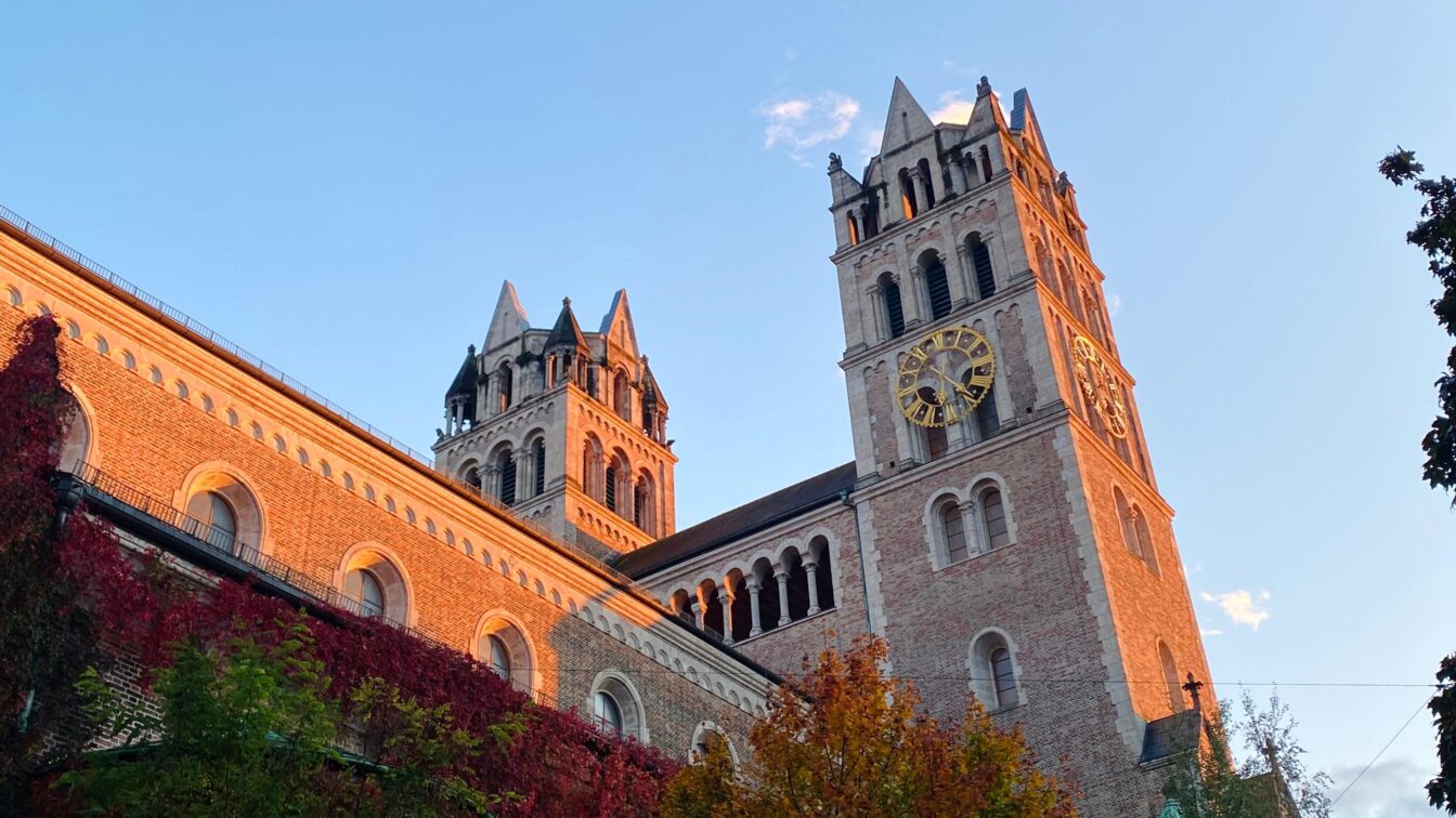 Zwei Kirchtürme, die von der untergehenden Sonne angestrahlt werden.
