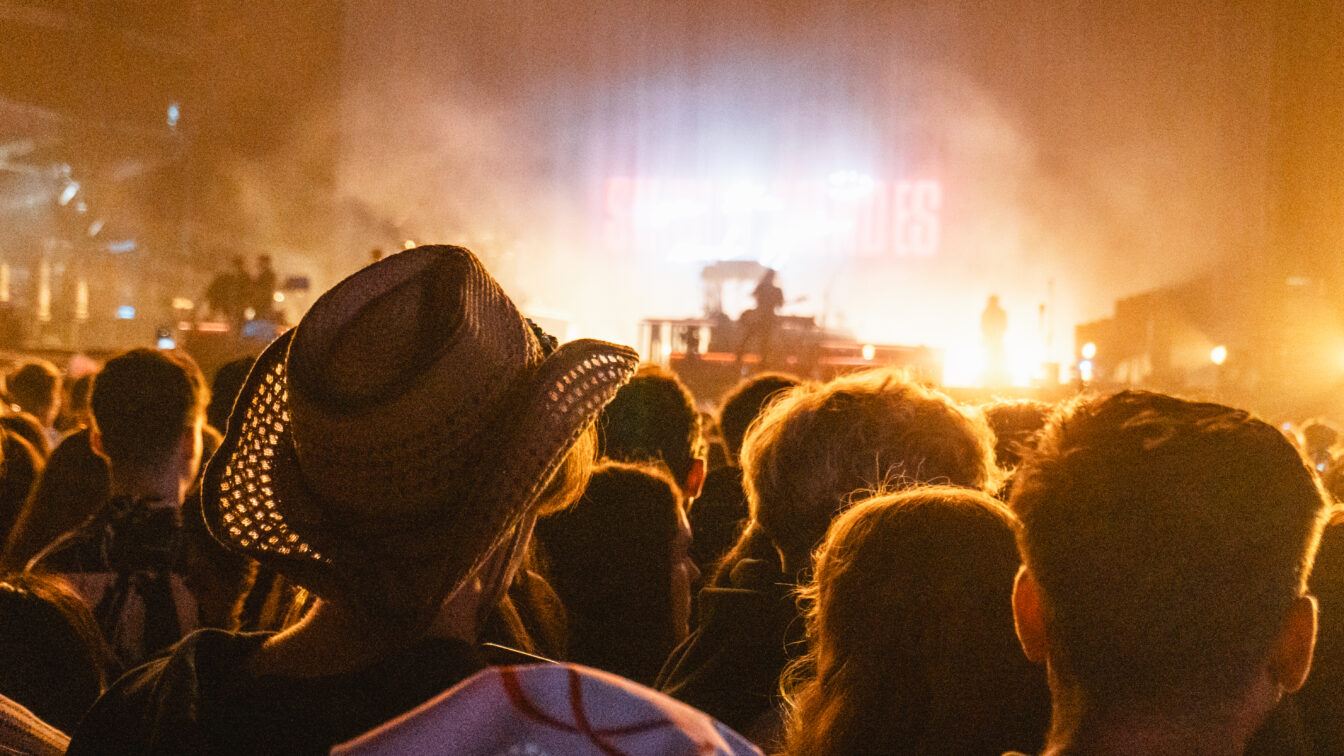 Menschenmenge bei Konzert mit Bühnenbeleuchtung, Festival-Atmosphäre wie bei einer Party in Berlin Friedrichshain, Open-Air-Event mit Livemusik
