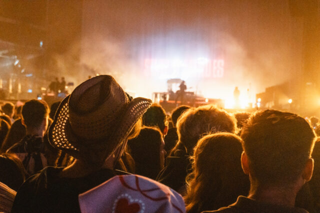 Menschenmenge bei Konzert mit Bühnenbeleuchtung, Festival-Atmosphäre wie bei einer Party in Berlin Friedrichshain, Open-Air-Event mit Livemusik