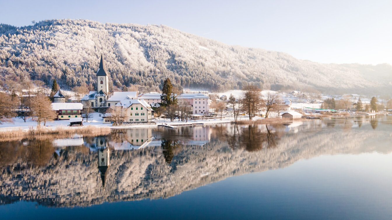 Blick auf eine Kirche am Ossiacher See in verschneiter Landschaft
