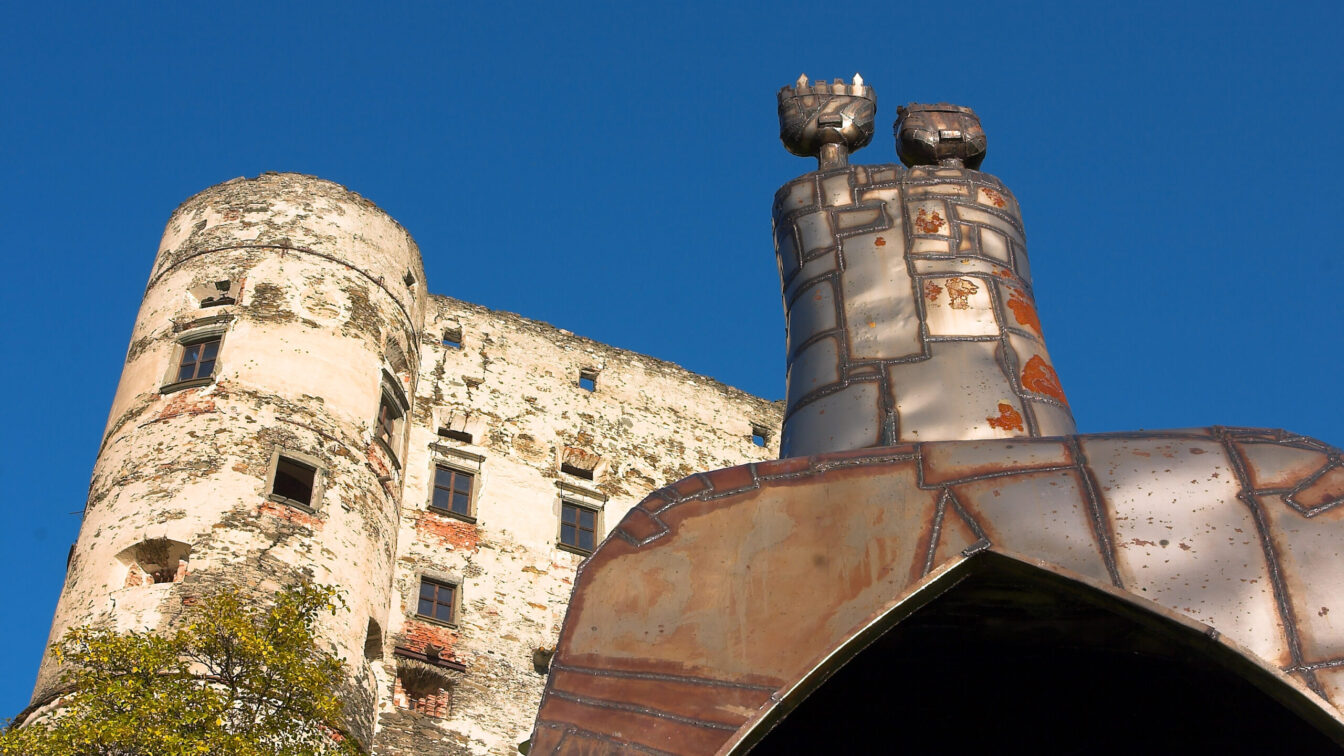 Alte Burg in der Künstlerstadt Gmünd mit moderner Metallskulptur im Vordergrund vor blauem Himmel