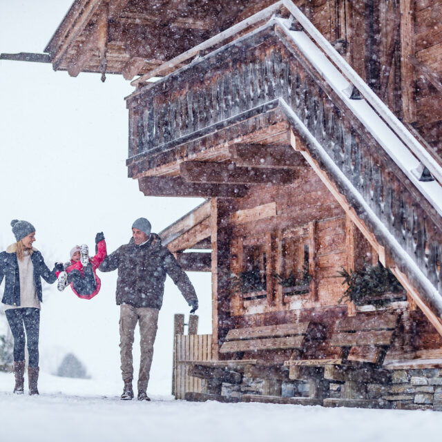 Eltern mit Kind neben Hoteleingang im Winter