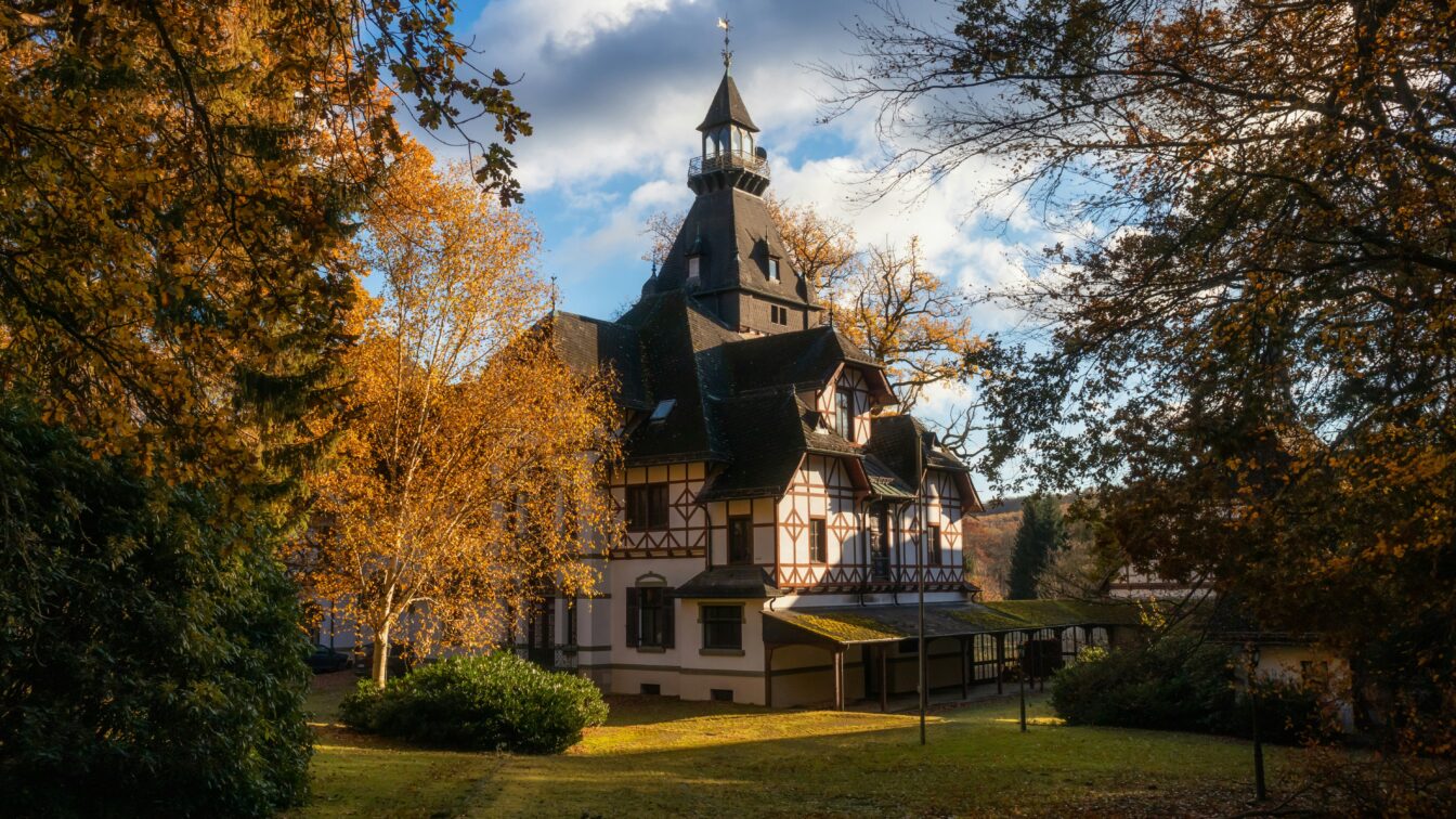 Malereisches Fachwerkhaus inmitten herbstlich gefärbter Bäume im Sonnenschein, idealer Ausflugsort in Deutschland im Herbs
