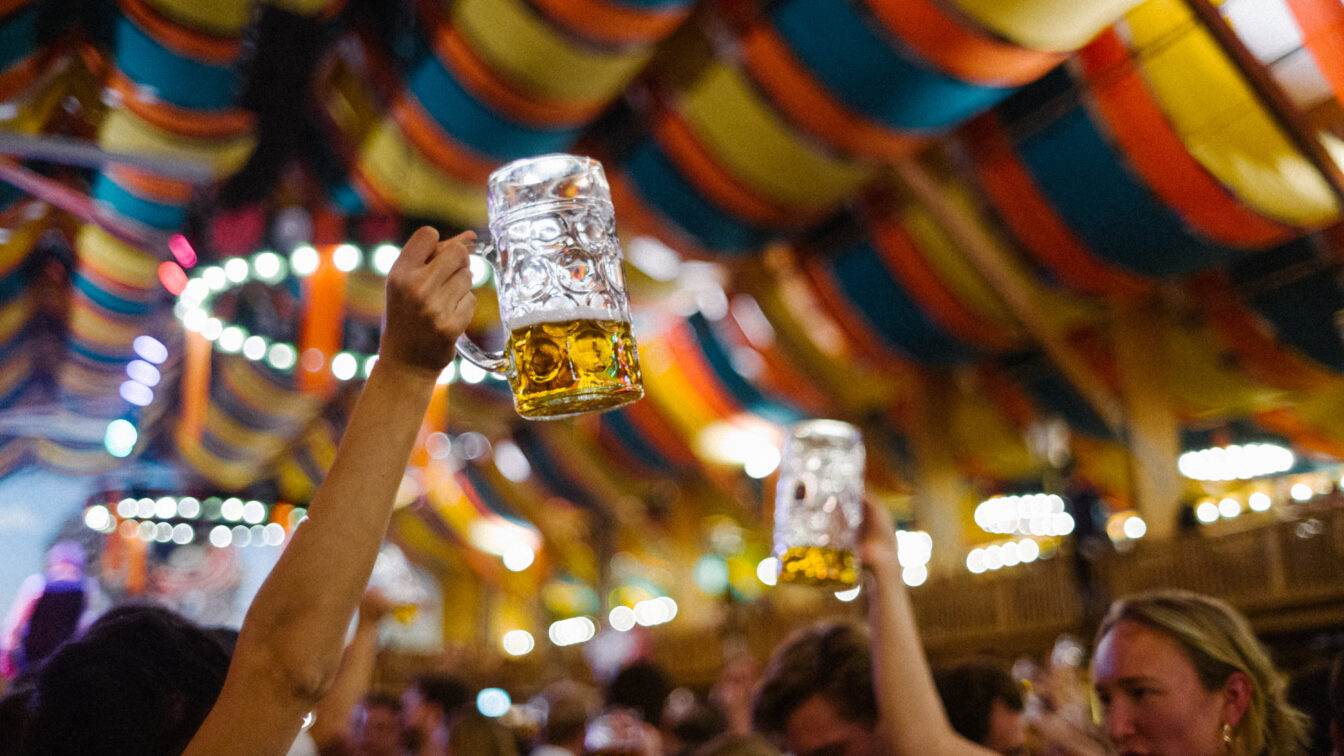 Masskrüge in einem Festzelt, die in die Höhe gehoben werden