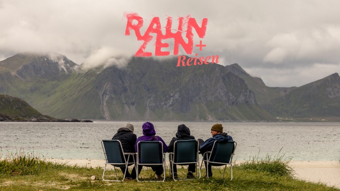 Vier Reisende sitzen gemeinsam am Strand in Campingstühlen und blicken auf Meer und Berge – entspannte Gruppenreise in die Natur mit Abenteuer-Feeling.