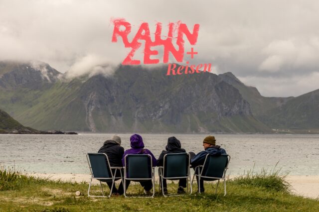 Vier Reisende sitzen gemeinsam am Strand in Campingstühlen und blicken auf Meer und Berge – entspannte Gruppenreise in die Natur mit Abenteuer-Feeling.