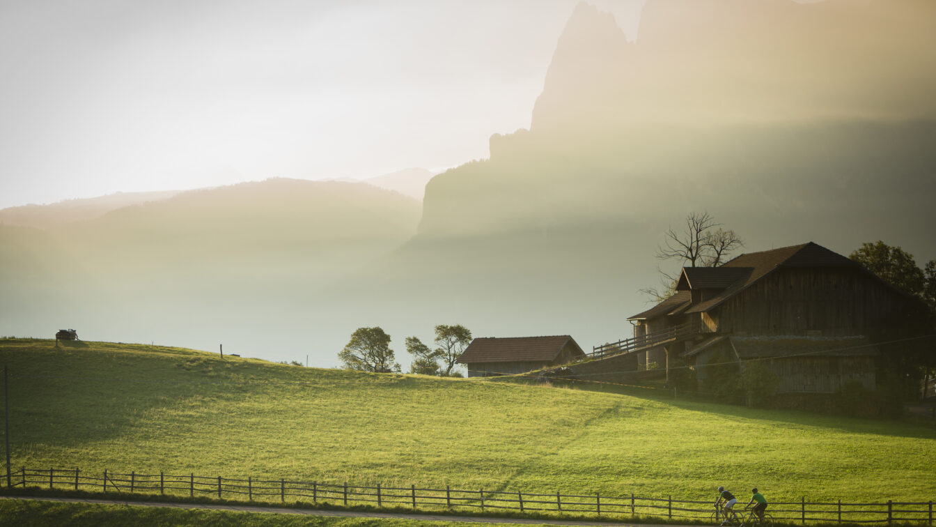 Geheimtipp für Wandern in Südtirol: idyllische Landschaft am Ritten mit traditionellem Bauernhof, grünen Wiesen und Abendsonne über den Dolomiten – perfekte Kulisse für Naturgenuss und entspannte Wanderungen.