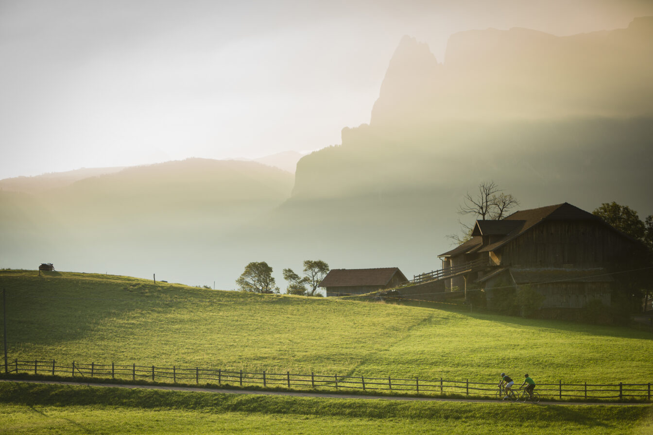 Geheimtipp für Wandern in Südtirol: idyllische Landschaft am Ritten mit traditionellem Bauernhof, grünen Wiesen und Abendsonne über den Dolomiten – perfekte Kulisse für Naturgenuss und entspannte Wanderungen.