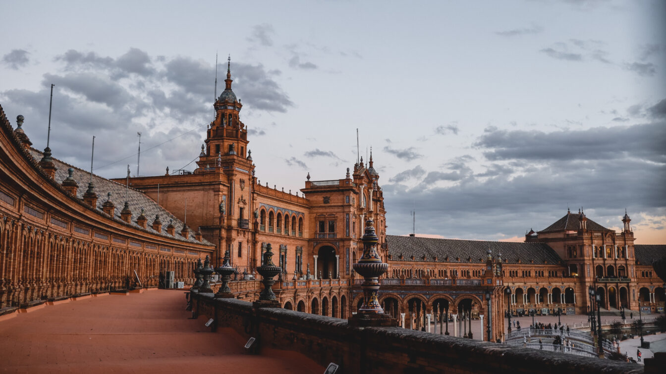 Plaza de España in Sevilla, Spanien, bei Sonnenuntergang mit rotgoldenem Licht auf den historischen Gebäuden – ein beliebtes Reiseziel für einen herbstlichen Städtetrip im Oktober in Europa.