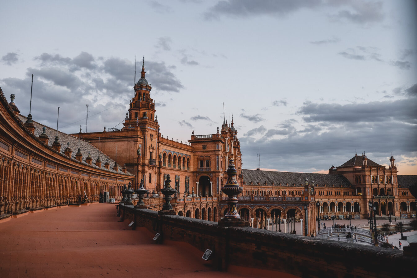 Plaza de España in Sevilla, Spanien, bei Sonnenuntergang mit rotgoldenem Licht auf den historischen Gebäuden – ein beliebtes Reiseziel für einen herbstlichen Städtetrip im Oktober in Europa.