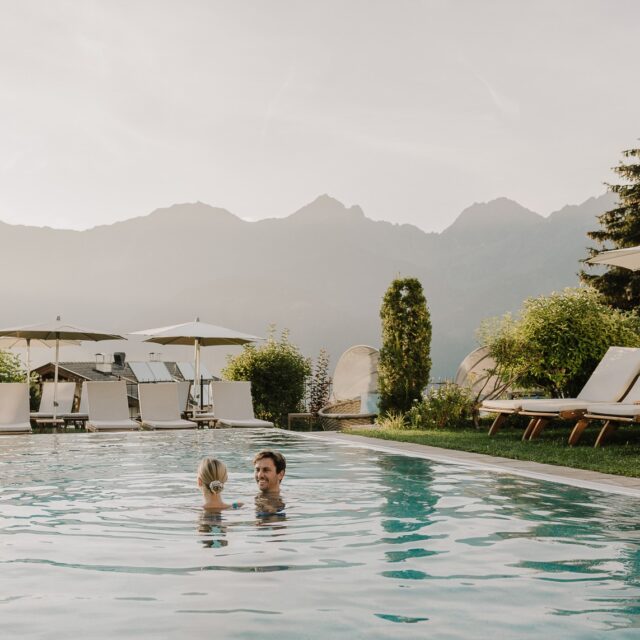 Zwei Personen schwimmen im Sommer im Outdoor-Pool eines Hotels.