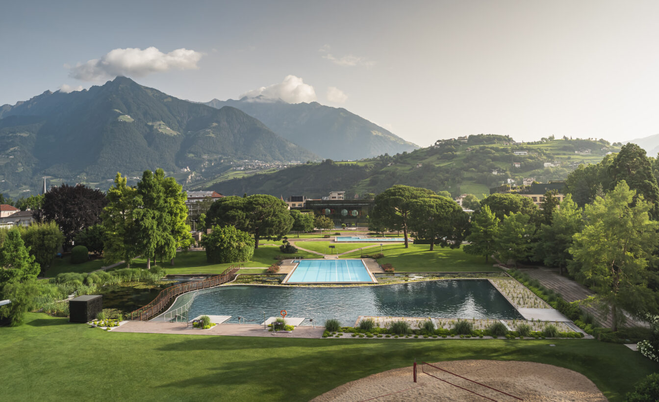 Therme Meran in Südtirol mit Außenpools und weitläufiger Parkanlage, umgeben von grünen Hügeln und imposanten Alpen im Hintergrund – ideal für Wellness, Entspannung und Naturerlebnis.