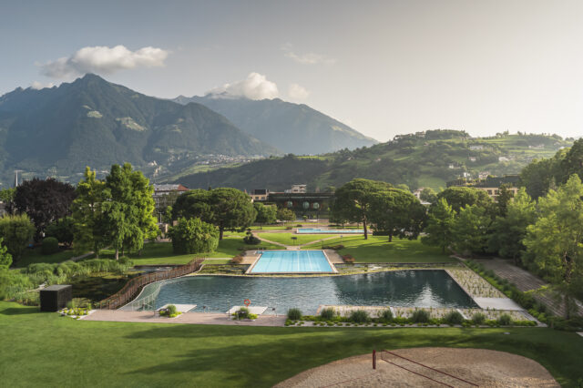 Therme Meran in Südtirol mit Außenpools und weitläufiger Parkanlage, umgeben von grünen Hügeln und imposanten Alpen im Hintergrund – ideal für Wellness, Entspannung und Naturerlebnis.