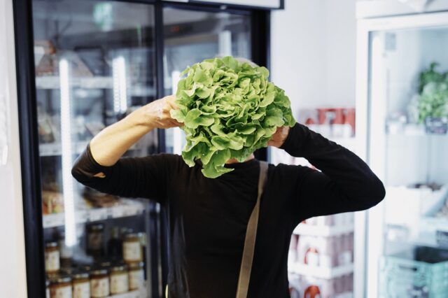 Person mit Salat vor dem Gesicht - im Mila Mitmachsupermarkt Wien