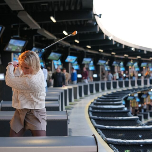 Frau beim Abschlag bei Topgolf